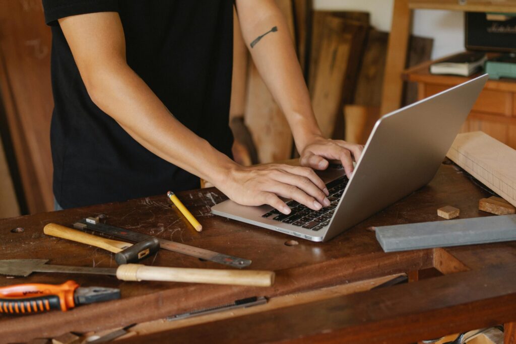 Handwerker mit Laptop in Werkstatt in Kitzingen, zeigt digitale Erreichbarkeit.